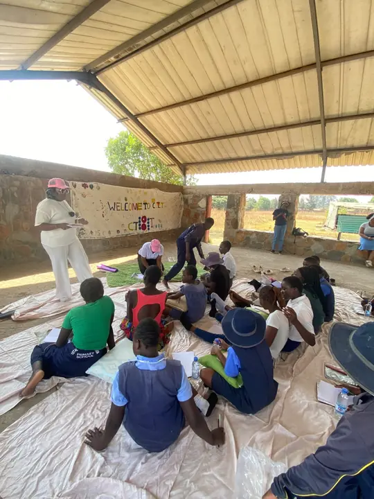 Girls and facilitators sit together in a large school-based circle.