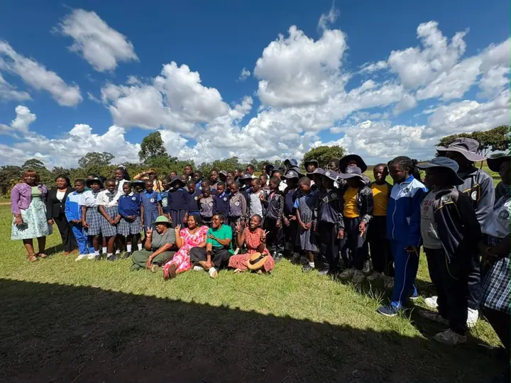 Girls and facilitators standing together outdoors under a bright sky.