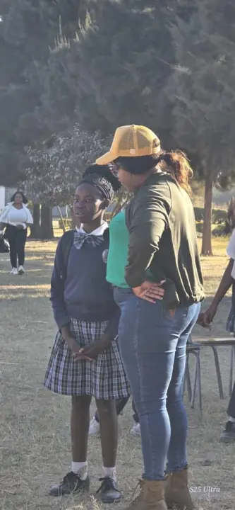 An adult mentor listens closely to a schoolgirl outdoors.